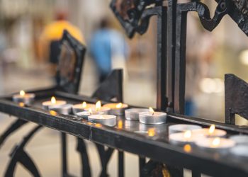 Lots of small candles in a catholic church in daylight.