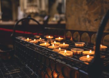 Many small candles in a Catholic church in a dark interior.